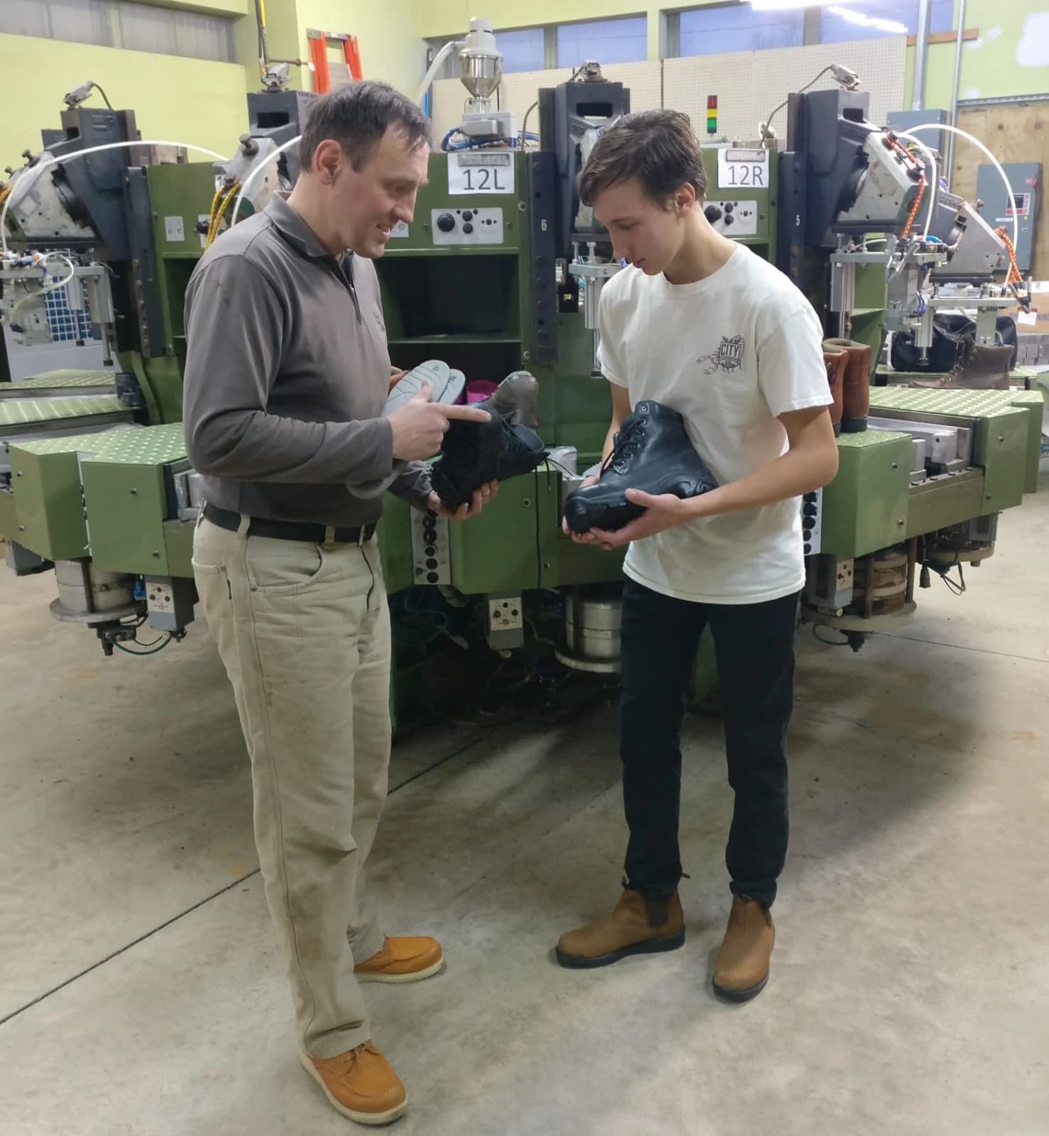 Petr Kovarik inspecting a handcrafted work boot with his son at the Liberty Footwear factory
